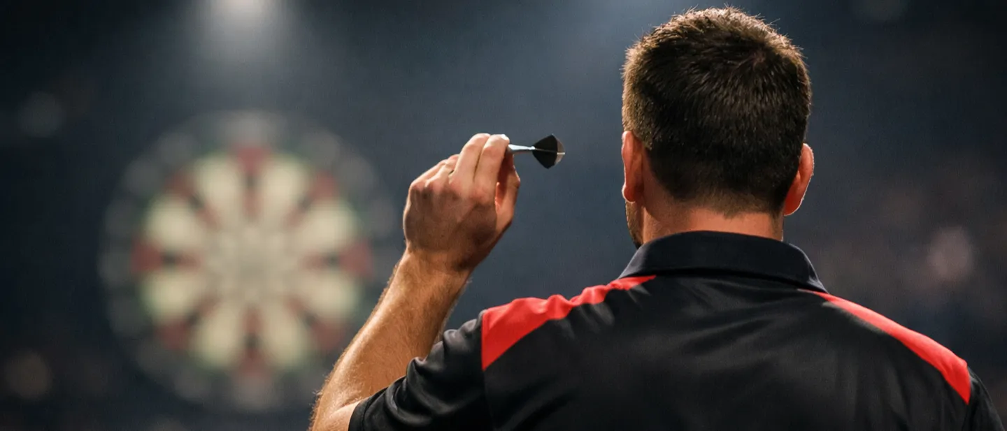 Dartspieler wirft auf die Scheibe unter Scheinwerferlicht in einer vollen Arena